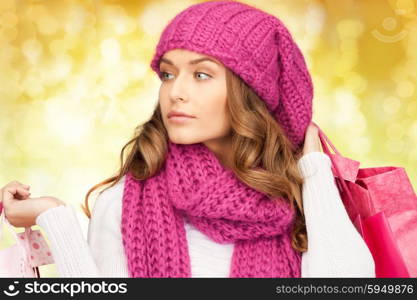 holidays, christmas, sale and people concept - young woman in winter clothes with shopping bags over lights background