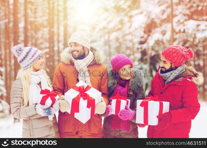 holidays, christmas, season, friendship and people concept - group of smiling friends with gift boxes in winter forest