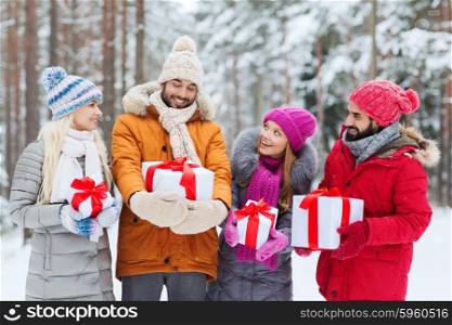 holidays, christmas, season, friendship and people concept - group of smiling friends with gift boxes in winter forest
