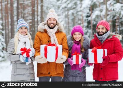 holidays, christmas, season, friendship and people concept - group of smiling friends with gift boxes in winter forest