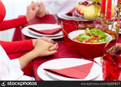 holidays, christmas, thanksgiving day and people concept - family having dinner and praying at home. family having holiday dinner and praying at home