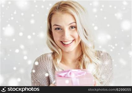 holidays, christmas, winter and people concept - happy young woman gift box or present over snow. happy young woman with gift box