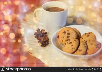 holidays, christmas, winter, food and drinks concept - close up of cups with hot chocolate or cocoa drinks and oat cookies on white fur rug over lights