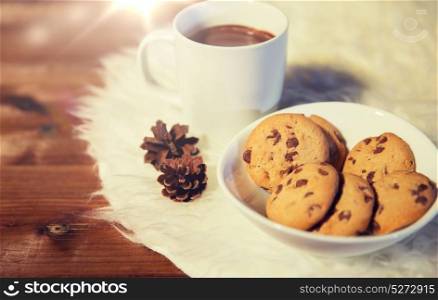 holidays, christmas, winter, food and drinks concept - close up of cups with hot chocolate or cocoa drinks and oat cookies on white fur rug. cups of hot chocolate with cookies on fur rug