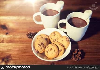 holidays, christmas, winter, food and drinks concept - close up of cups with hot chocolate or cocoa drinks and marshmallow with oat cookies on wooden table. cups of hot chocolate with marshmallow and cookies