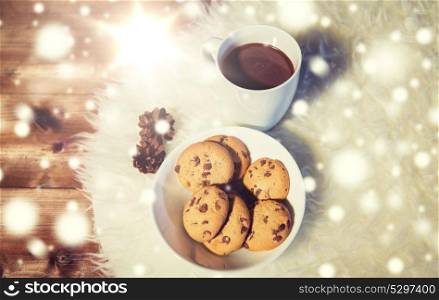holidays, christmas, winter, food and drinks concept - close up of cups with hot chocolate or cocoa drinks and oat cookies on white fur rug. cups of hot chocolate with cookies on fur rug