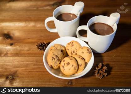 holidays, christmas, winter, food and drinks concept - close up of cups with hot chocolate or cocoa drinks and marshmallow with oat cookies on wooden table
