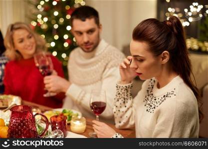 holidays, communication and celebration concept - young woman calling on smartphone and having christmas dinner with friends at home. woman calling on smartphone at christmas dinner