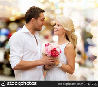 holidays, dating, people and dating concept - happy couple with bunch of flowers over lights background