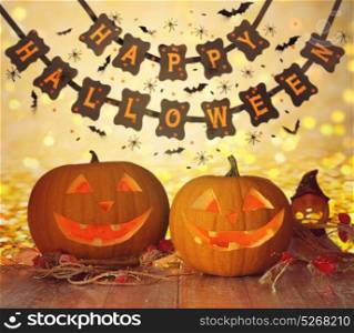 holidays, decoration and celebration concept - jack-o-lantern or pumpkins and happy halloween festive garland or banner over lights background. carved pumpkins and happy halloween garland