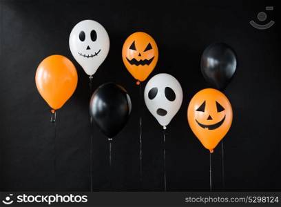 holidays, decoration and party concept - air balloons with funny and evil faces for halloween on black background. scary air balloons decoration for halloween party