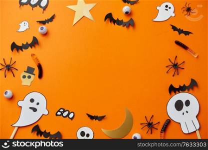 holidays, decoration and party concept - halloween paper decorations and sweets with blank copy space on orange background. halloween party paper decorations and sweets
