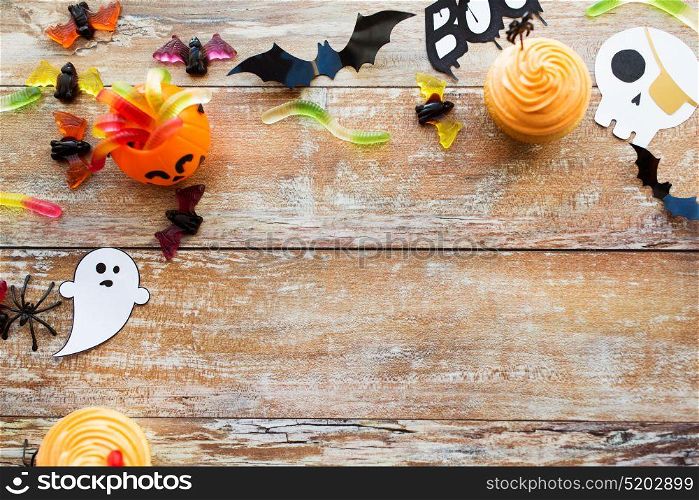 holidays, decoration and party concept - halloween paper decorations and treats with blank copy space on wooden boards background. halloween party paper decorations and treats