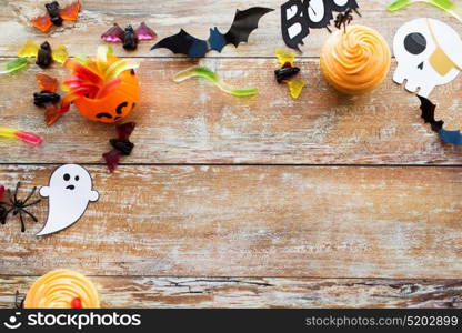 holidays, decoration and party concept - halloween paper decorations and treats with blank copy space on wooden boards background. halloween party paper decorations and treats