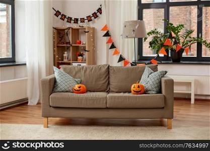 holidays, decoration and party concept - home room with jack-o-lanterns or pumpkins on sofa and halloween decorations. jack-o-lanterns and halloween decorations at home