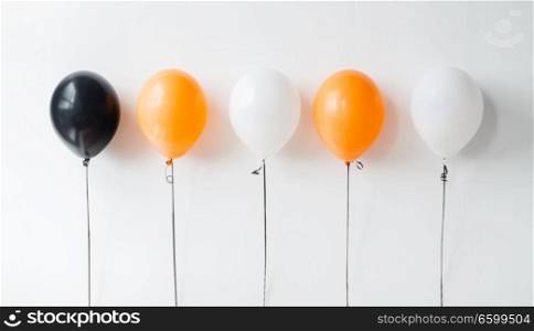 holidays, decoration and party concept - orange, black and white air balloons for halloween or birthday on white background. air balloons for halloween or birthday party