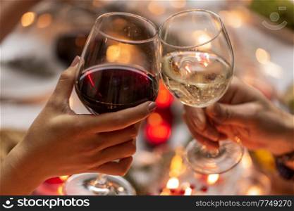 holidays, drinks and celebration concept - close up of hands toasting wine glasses at dinner party on christmas at home. close up of hands toasting wine at christmas party