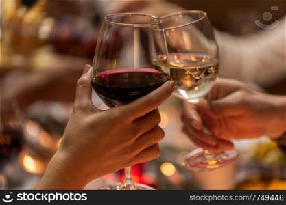 holidays, drinks and celebration concept - close up of hands toasting wine glasses at dinner party on christmas at home. close up of hands toasting wine at christmas party