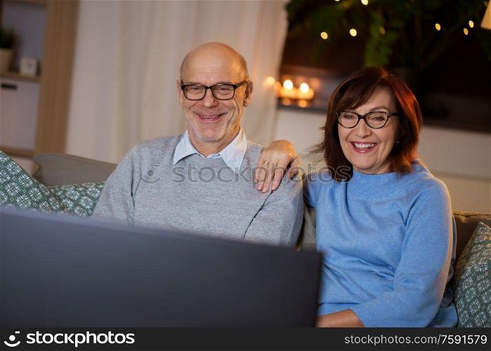 holidays, drinks and people concept - happy smiling senior couple watching tv at home in evening. happy senior couple watching tv at home