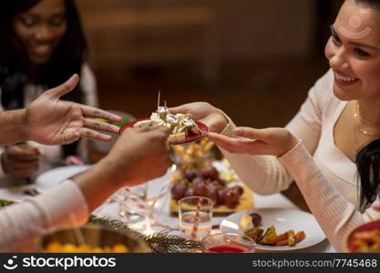 holidays, eating and celebration concept - close up of friends having christmas dinner at home and sharing food. close up of people share food at christmas dinner