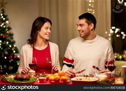 holidays, eating and celebration concept - happy couple having christmas dinner at home. happy couple eating at christmas dinner