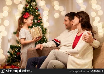 holidays, family and celebration concept - happy mother, father and little daughter with christmas present at home. happy family with christmas present at home
