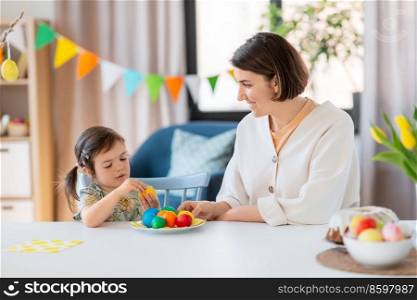 holidays, family and people concept - happy mother and little baby daughter with colored easter eggs at home. mother and child with colored easter eggs at home