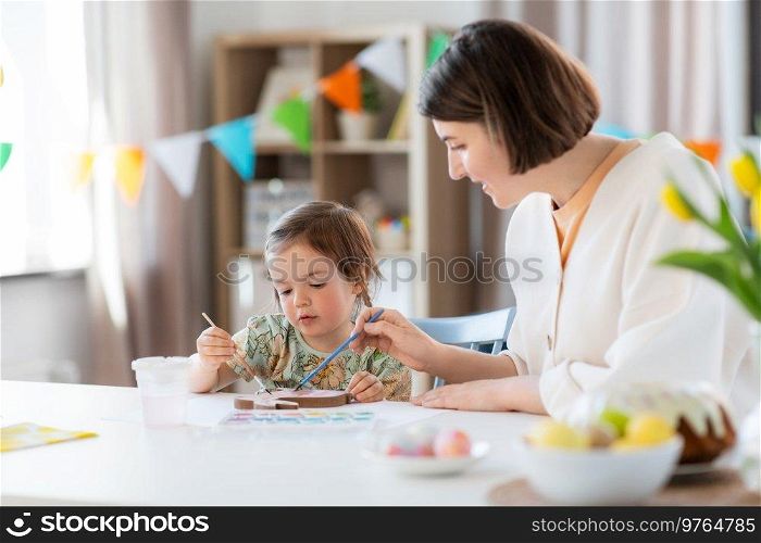 holidays, family and people concept - happy mother and little baby daughter coloring easter bunny with watercolors at home. mother with child coloring easter bunny at home