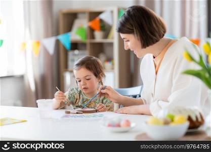 holidays, family and people concept - happy mother and little baby daughter coloring easter bunny with watercolors at home. mother with child coloring easter bunny at home