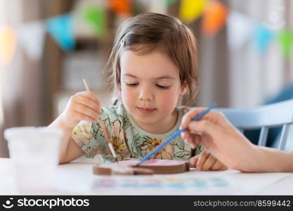 holidays, family and people concept - mother and little baby daughter coloring easter bunny with watercolors at home. mother with child coloring easter bunny at home