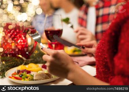 holidays, food and celebration concept - close up of friends having christmas dinner and eating. close up of friends having christmas dinner