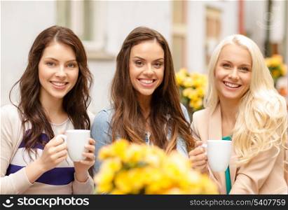 holidays, food and tourism concept - three beautiful girls drinking coffee in cafe