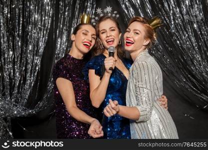 holidays, friends and people concept - three women s with microphone singing karaoke at christmas party. women with microphone singing at christmas party