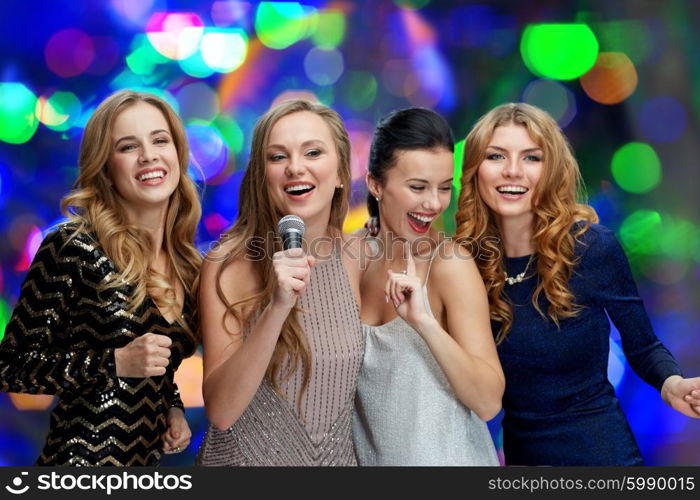 holidays, friends, bachelorette party, nightlife and people concept - three women in evening dresses with microphone singing karaoke over lights background