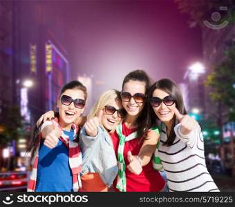 holidays, friendsip, nightlife and happy people concept - happy teenage girls or young women showing thumbs up over night city background