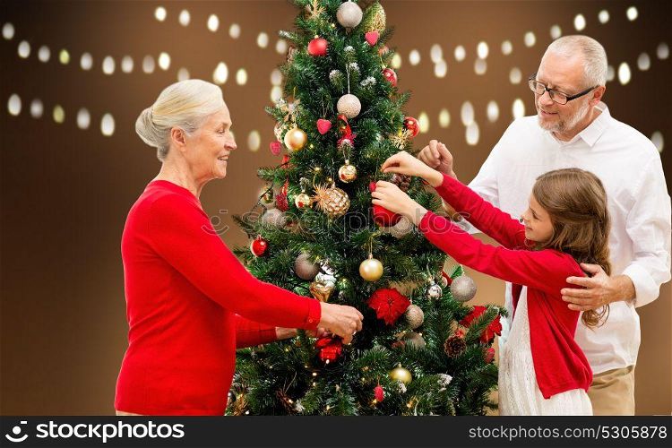 holidays, generation and people concept - happy family decorating christmas tree over lights background. happy family decorating christmas tree