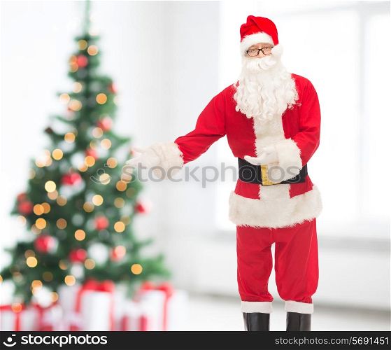 holidays, gesture and people concept - man in costume of santa claus over living room and christmas tree background