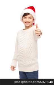 holidays, gesture, christmas, childhood and people concept - smiling happy boy in santa hat showing thumbs up