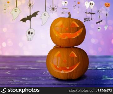 holidays, halloween and decoration concept - close up of carved pumpkins on table over lights and party garland background. close up of halloween pumpkins on table