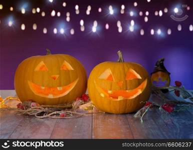 holidays, halloween and decoration concept - close up of carved pumpkins on table over ultra violet background. close up of halloween pumpkins on table