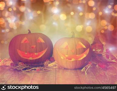 holidays, halloween and decoration concept - close up of carved pumpkins with smiley faces on table over lights