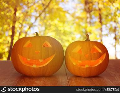 holidays, halloween and decoration concept - close up of pumpkins on wooden table over natural background