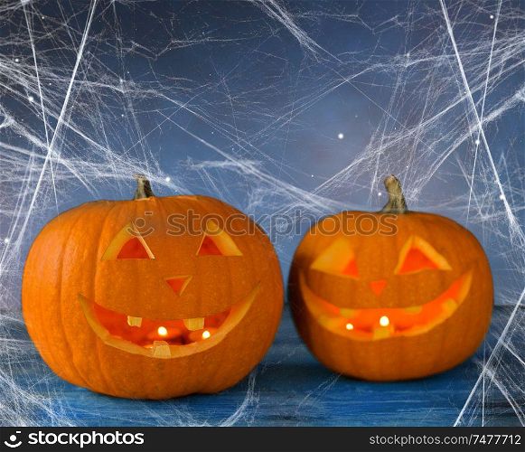 holidays, halloween and decoration concept - two pumpkins or jack o lanterns on table and spiderweb over starry night sky background. two pumpkins or jack o lanterns and spiderweb