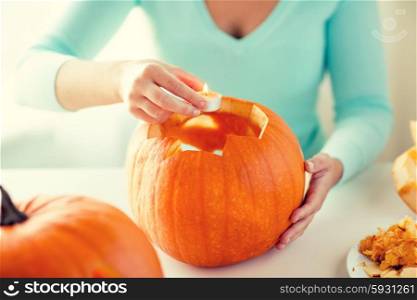 holidays, halloween, decoration and people concept - close up of woman with pumpkins at home