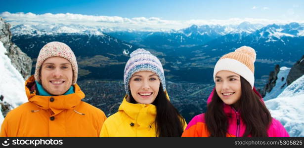 holidays, leisure and people concept - happy young friends in winter clothes at ski resort over alps mountains background. happy friends in winter over alps mountains