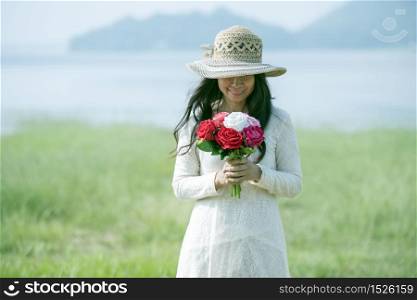 Holidays, love and flowers concept - young beautiful woman wear a white lace dress with bouquet of flowers.