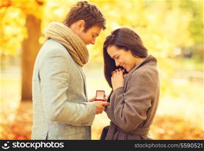 holidays, love, couple, relationship and dating concept - romantic man proposing to a woman in the autumn park