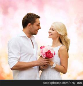 holidays, love, people and dating concept - happy couple with bunch of flowers over pink lights background