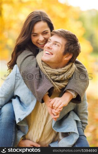 holidays, love, travel, tourism, relationship and dating concept - romantic couple playing in the autumn park