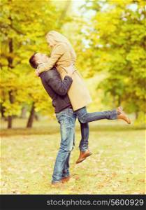 holidays, love, travel, tourism, relationship and dating concept - romantic couple playing in the autumn park